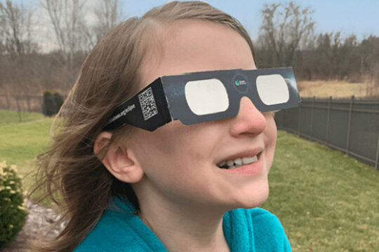 child wearing approved solar eclipse glasses